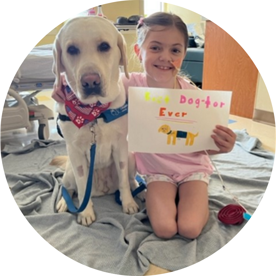 A girl sits with a dog holding sign that says 
