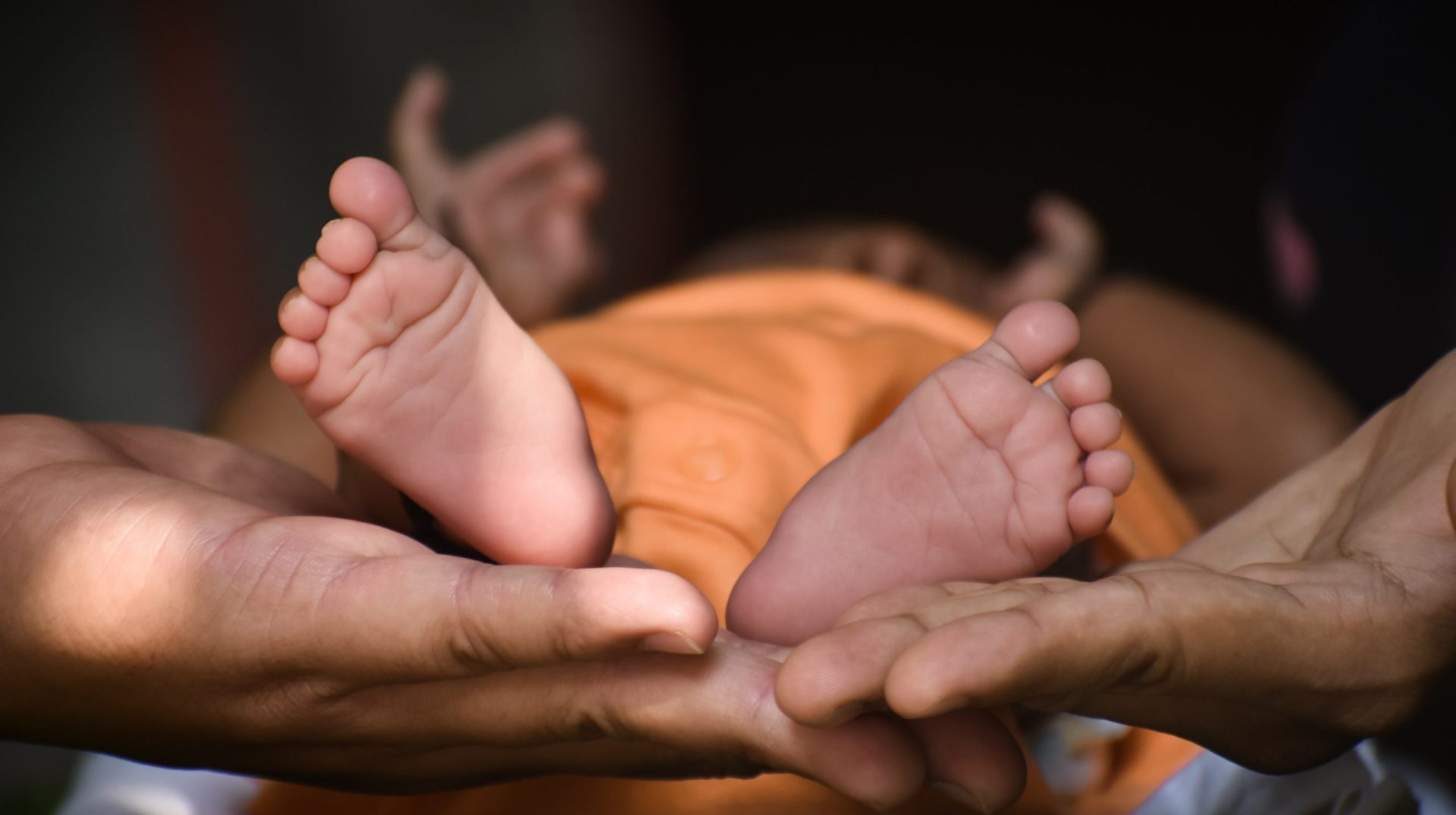 A woman gently holds a tiny baby's foot on a soft blanket, showcasing the tender bond between mother and child.